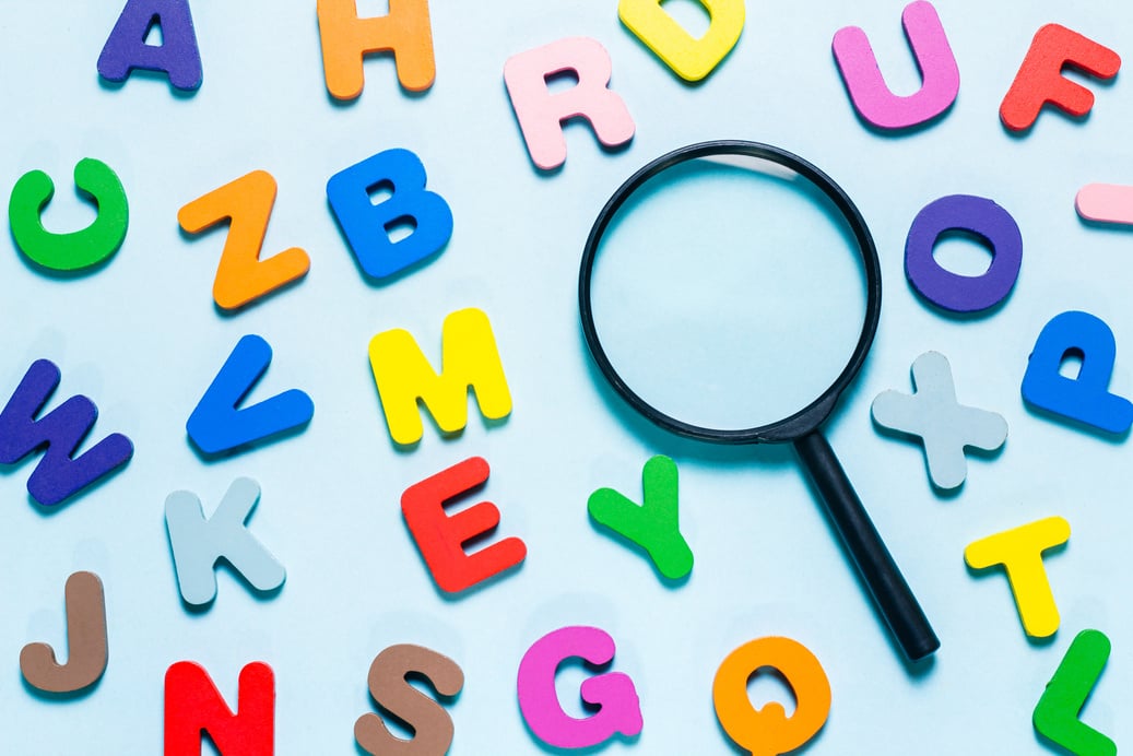 English alphabet made of square wooden tiles with the English alphabet scattered on blue background. The concept of thinking development, grammar.